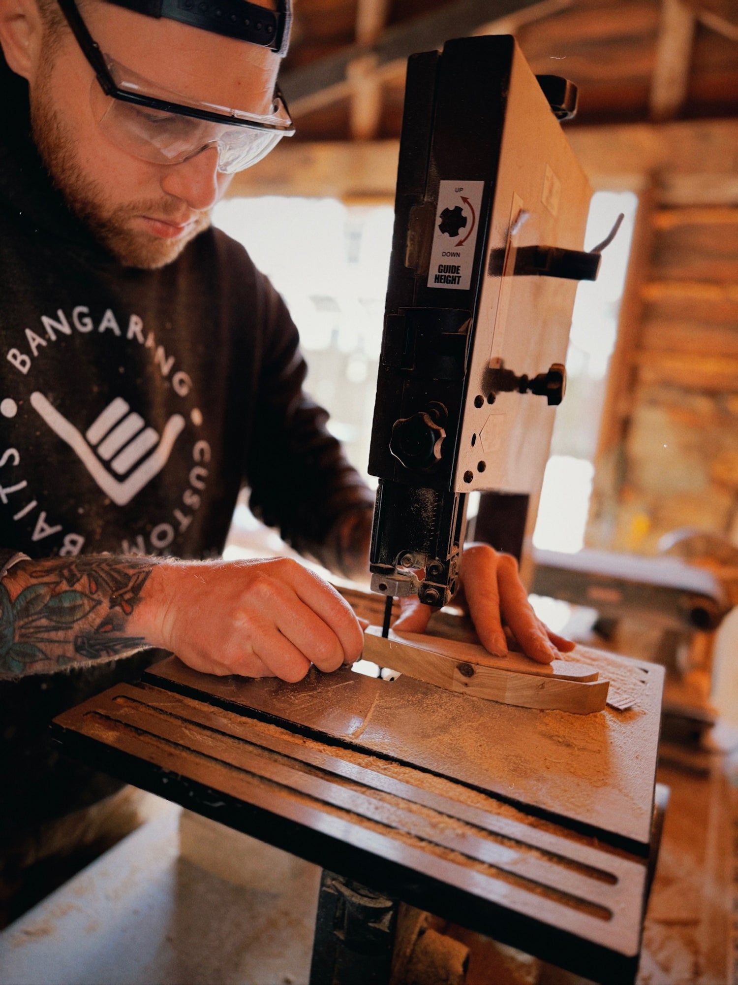 Bangarang owner using a band saw in a workshop wearing protective eyewear.